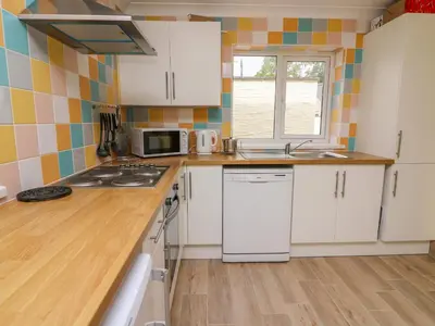 a kitchen with white cabinets and a sink and a microwave at Hen Brynbedw in Llanybydder