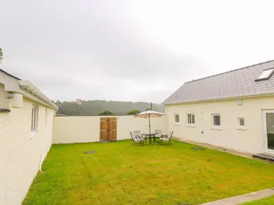 a patio with a table and chairs and an umbrella at Hen Brynbedw in Llanybydder