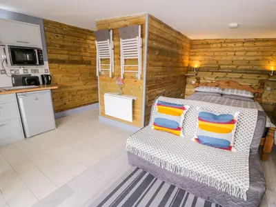 a bedroom with a bed and a kitchen at Cilan Lodge in Corwen
