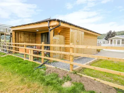 a wooden house with a fence around it at Cilan Lodge in Corwen