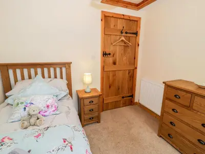 a teddy bear sitting on a bed in a bedroom at Yr Hen Stabal in Blaenau-Ffestiniog