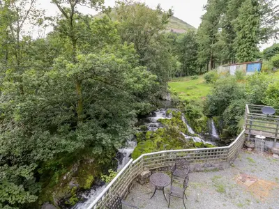 a table and chairs next to a waterfall at Dyfi Cottage in Machynlleth