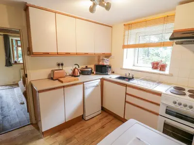 a kitchen with white cabinets and a sink at Dyfi Cottage in Machynlleth