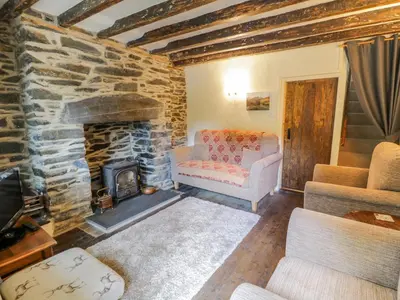 a living room with a stone fireplace and a couch at Dyfi Cottage in Machynlleth