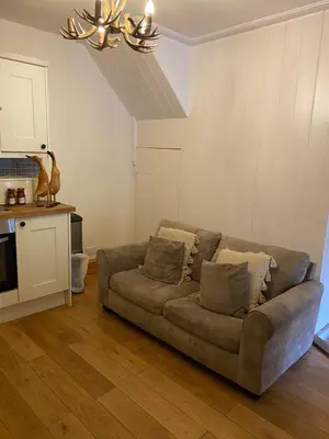 a living room with a couch and a kitchen at Romantic Cottage with Wood-fired Hot tub and Outdoor Pizza Oven in Shrewsbury