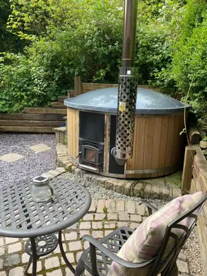an outdoor hot tub with a table and a stove at Romantic Cottage with Wood-fired Hot tub and Outdoor Pizza Oven in Shrewsbury