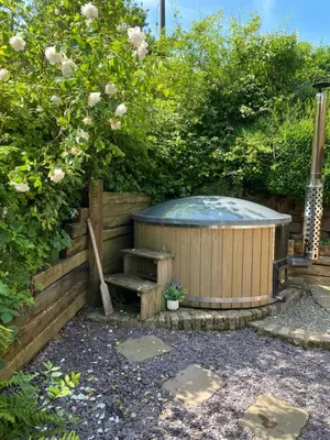 a hot tub with a bench in a garden at Romantic Cottage with Wood-fired Hot tub and Outdoor Pizza Oven in Shrewsbury