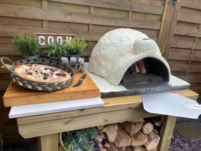a pizza oven sitting on top of a wooden table at Romantic Cottage with Wood-fired Hot tub and Outdoor Pizza Oven in Shrewsbury