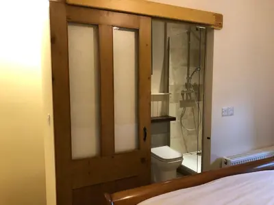 a bathroom with a toilet and a glass door at Romantic Cottage with Wood-fired Hot tub and Outdoor Pizza Oven in Shrewsbury