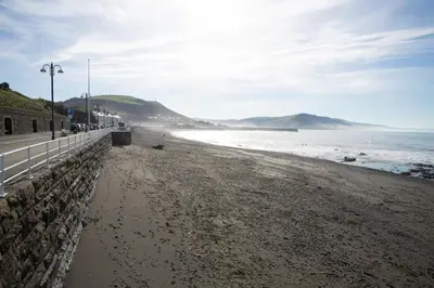 a sandy beach with a fence and the ocean at 1 Lisburne House in Aberystwyth