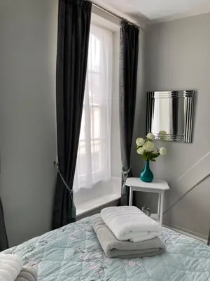 a bedroom with a bed with a window and a vase of flowers at Assembly View - two bedroomed apartment with parking permit in Ludlow Town Centre in Ludlow