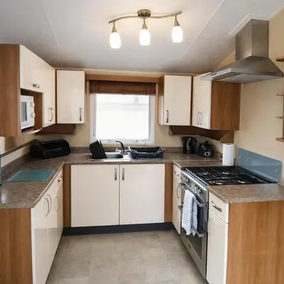 a kitchen with white cabinets and a stove top oven at Clwyd 6 in Borth