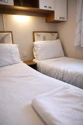 two beds in a hotel room with white sheets at Clwyd 6 in Borth