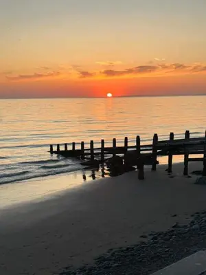 a pier on the beach with the sunset in the background at Cliff haven in Borth