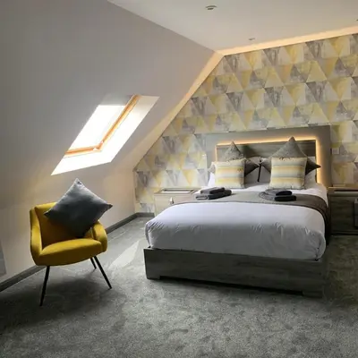 a bedroom with a bed and a yellow chair at Sunset Studio Apartments in Aberaeron