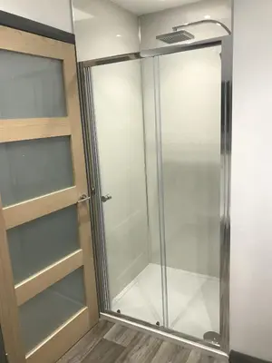 a shower with glass doors in a room at Sunset Studio Apartments in Aberaeron