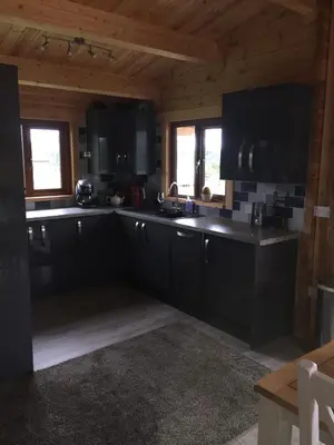 a large kitchen with black cabinets and windows at RedWood Lodge in Ludlow