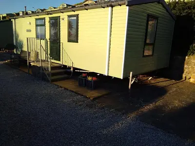 a small house with a porch and a deck at Hendre Coed Isaf static caravan Barmouth in Barmouth