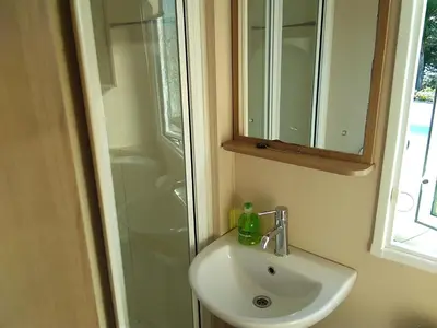 a bathroom sink with a shower and a mirror at Hendre Coed Isaf static caravan Barmouth in Barmouth