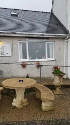a stone table and benches in front of a house at Hendre Coed Isaf static caravan Barmouth in Barmouth