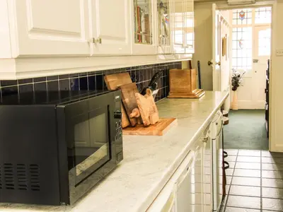 a kitchen with white cabinets and a black microwave at Sunningdale in Ludlow