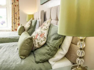 a bed with pillows on it with a green lamp at Sunningdale in Ludlow