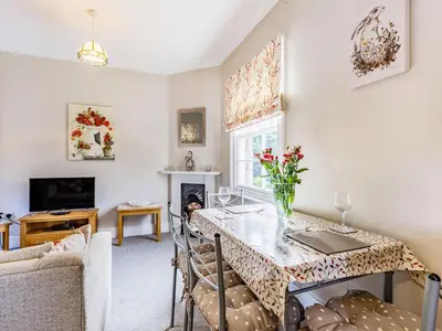 a living room with a table with a vase of flowers on it at Riverside in Craven Arms