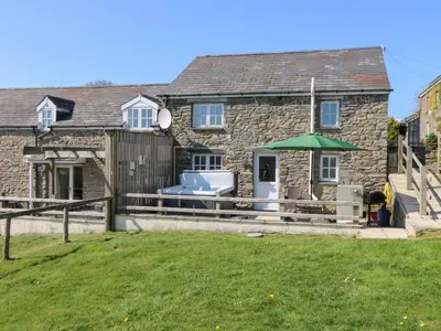 a stone house with a deck and a lawn at The Stable in Lampeter