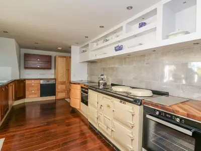 a large kitchen with wooden floors and white cabinets at The Pheasantry in Builth Wells