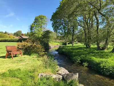 a wooden bench sitting next to a river at Maesyfelin Isaf Apartment in Llanybydder