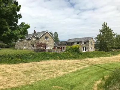 an old house in a field with a yard at Maesyfelin Isaf Apartment in Llanybydder