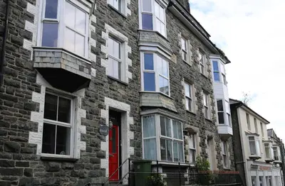 a brick building with a red door on a street at Central Barmouth Town House - Near Beach - Sleeps up to 16! in Barmouth