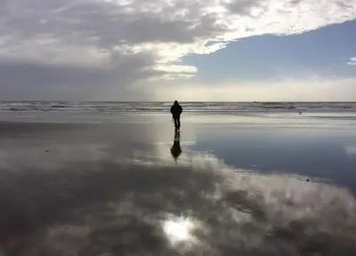a person walking on the beach near the ocean at Central Barmouth Town House - Near Beach - Sleeps up to 16! in Barmouth