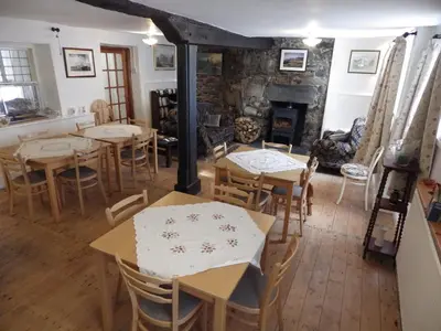 a dining room with tables and chairs and a fireplace at Aber Cottage B&B in Dolgellau