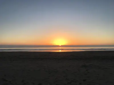 a sunset on the beach with the sun setting at Aber Cottage B&B in Dolgellau