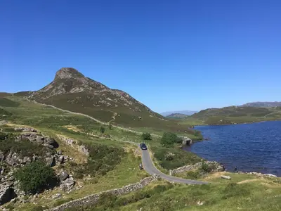 a road on a hill next to a body of water at Aber Cottage B&B in Dolgellau