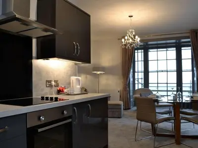 a kitchen with black cabinets and a dining room at Grosvenor House APT 1 in Aberystwyth