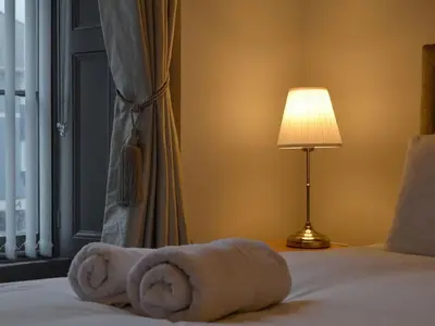 a bed with a towel on it next to a lamp at Grosvenor House APT 1 in Aberystwyth