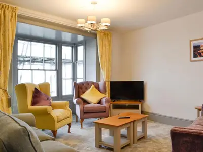 a living room with a couch and chairs and a tv at Grosvenor House APT 2 in Aberystwyth
