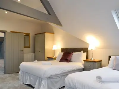 two beds in a hotel room with two lamps at Grosvenor House APT 2 in Aberystwyth