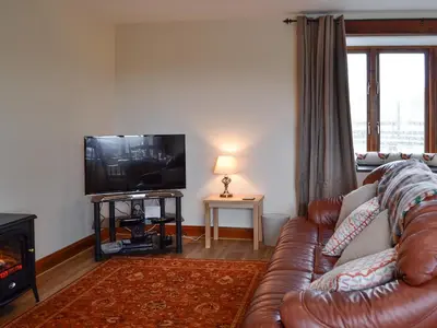 a living room with a leather couch and a television at Trefechan in Pumpsaint