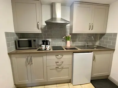 a kitchen with white cabinets and a sink and a refrigerator at Seven Stars Inn in Builth Wells