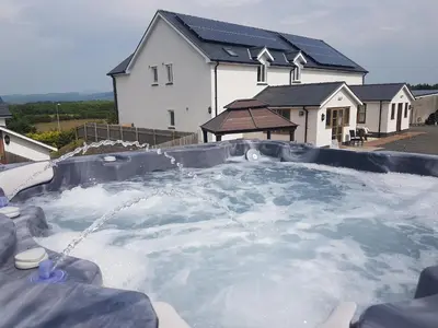 a hot tub filled with water in front of a house at Brynhyfryd in Aberystwyth