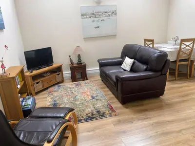 a living room with a leather couch and a tv at The Snicketts in Ludlow