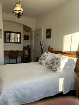 a bedroom with a bed with white sheets and pillows at Greylands Guest House in Llandrindod Wells