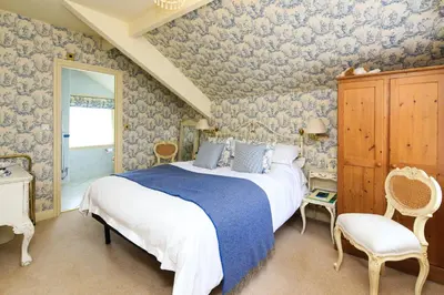 a bedroom with a large bed and blue wallpaper at The Old Vicarage Dolfor in Newtown