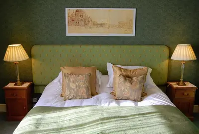 a bedroom with a bed with two nightstands and two lamps at The Old Vicarage Dolfor in Newtown