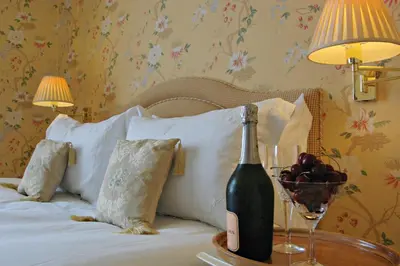 a bottle of wine on a table next to a bed at The Old Vicarage Dolfor in Newtown