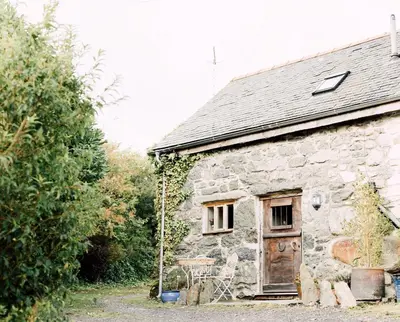 an old stone cottage with a wooden door and a porch at The Stable at Ty Beic in Bala