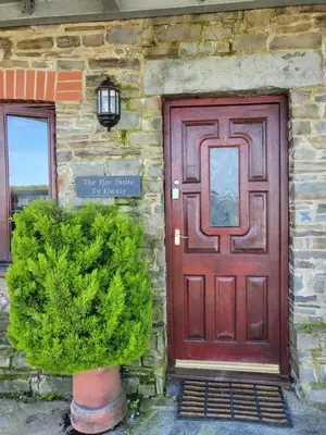 a red door on the side of a stone building at The Hay Suite in Aberystwyth